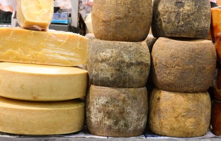 Cheese counter with many aged cheeses for sale in wheels or pieces