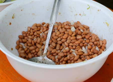 Large earthenware bowl filled with cooked beans and fresh onions at the village festival