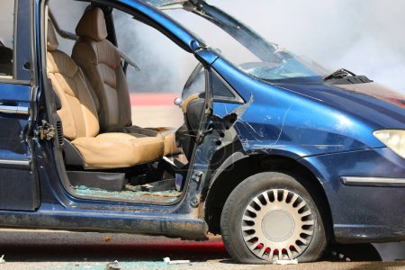 Zerstörtes Auto ohne Tür mit Scheibe auf dem Boden nach Gewalt von Randalierern in der Stadt