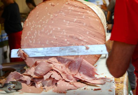 chef with a knife slicing a gigantic sausage called MORTADELLA GIGANTE in Italian language