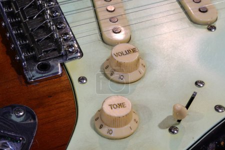 Close-up of electric guitar bridge with volume and tone knobs and pickups