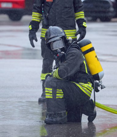Photo for Firefighters with  breathing apparatus with protective helmet with visors down during a rain emergency while it rains - Royalty Free Image
