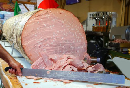 Italienische Salami namens Mortadella GIGANTE während des Dorffestes mit einem langen Messer aufgeschnitten