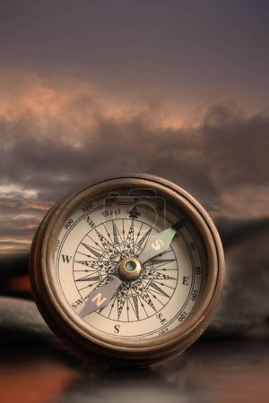 Téléchargez les photos : Vieille boussole en laiton utilisée pour la navigation avec un fond orageux - en image libre de droit