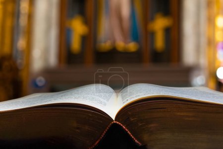 Foto de La Biblia muy antigua se abre delante de un altar católico cristiano - Imagen libre de derechos