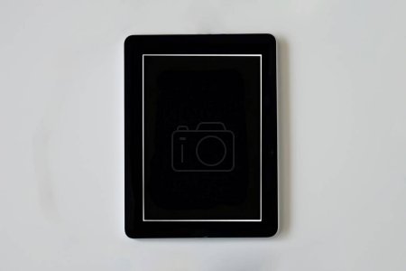Téléchargez les photos : Tablette utilisée pour internet avec un écran noir sur fond gris clair - en image libre de droit