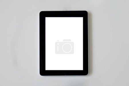 Téléchargez les photos : Tablette utilisée pour internet avec un écran blanc sur fond gris clair - en image libre de droit