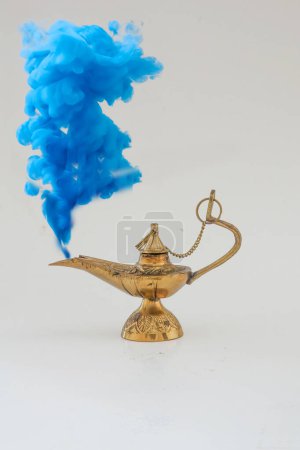 Foto de Lámpara de aceite vintage de latón sobre un fondo blanco sólido y humo azul - Imagen libre de derechos