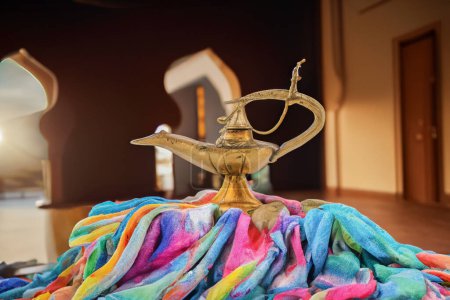 Téléchargez les photos : Vieille lampe à huile assise sur de beaux tissus colorés dans une pièce persane - en image libre de droit