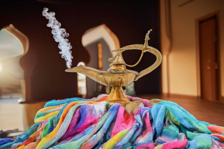 Téléchargez les photos : Vieille lampe à huile assise sur de beaux tissus colorés dans une pièce persane - en image libre de droit