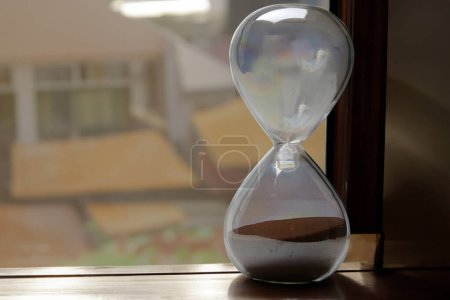 Foto de Reloj de arena cerca de una ventana durante el amanecer con luz dorada - Imagen libre de derechos
