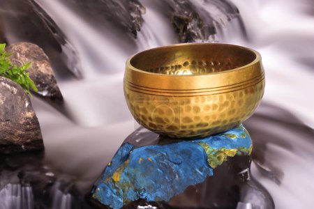 Photo for Water flows behind a Tibetan bowl creating a peaceful scene for meditation and spiritual growth - Royalty Free Image