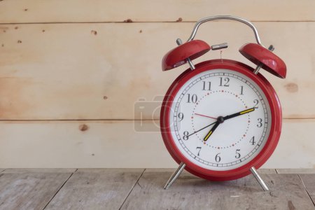 Téléchargez les photos : Réveil rouge rétro sur une surface en bois rustique avec un temps de réveil - en image libre de droit