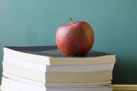 Photo for Red apple sits on a stack of books with a chalckboard in the background - Royalty Free Image