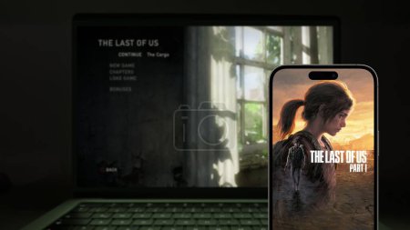 Foto de Estambul, Turquía - 21 de febrero de 2024: Last of Us Remastered Parte 1 visual on a smartphone screen and a laptop screen. Es un juego de Sony y Naughty Dog para Playstation y PC - Imagen libre de derechos