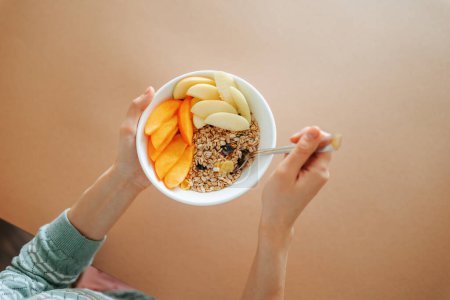 Photo for Copy space unrecognizable in female hands is a beautiful breakfast plate, juicy slices of raw fruit appetizingly lie on granola. A beautiful presentation is the key to success. - Royalty Free Image