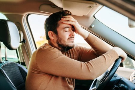 Photo for Clinging to steering wheel, closing his eyes and leaning on the drivers hand, the man is resting in the car. A common cause of accidents is fatigue at the wheel. You need to be able to rest on time. - Royalty Free Image