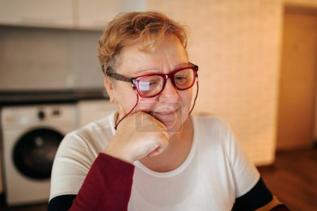 Téléchargez les photos : A Reflection of Authentic Beauty This photo captures the real, unapologetic beauty of a fat, older woman at home. She is depicted looking satisfied and happy, wearing glasses and showcasing - en image libre de droit