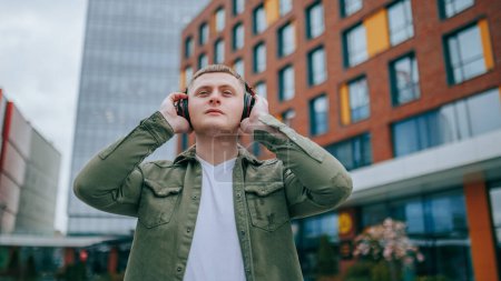 A guy with headphones on, walking and enjoying the beautiful city skyline in front of him. Rhythm in the City Handsome Man Listening to Music with Headphones