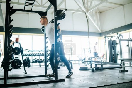 Un individuo motivado sudando hacia fuera en un gimnasio de entrenamiento, utilizando barras para participar en una variedad de ejercicios físicos, todo ello con el objetivo de mejorar la aptitud general y la fuerza.