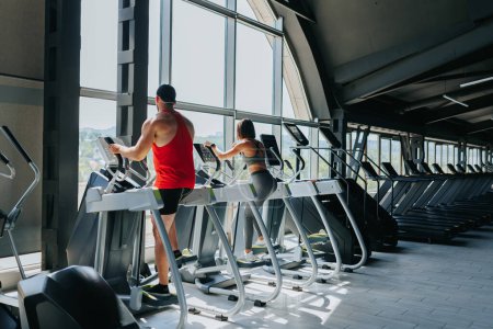 Indoor-Fitness-Enthusiasten, sowohl Männer als auch Frauen, nehmen an einem energiegeladenen Gruppen-Workout im Fitnessstudio teil und fördern die Vorteile eines gesunden Lebensstils.