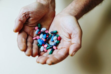 Foto de Montón de tabletas y pastillas de color se encuentra en la mano senil de la persona irreconocible. Los medicamentos se recetan para mejorar la salud. Muchas vitaminas.. - Imagen libre de derechos