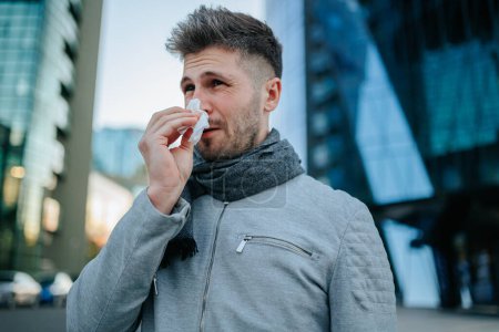 Entdecken Sie den Grippekampf eines jungen bärtigen hispanischen Amerikaners, veranschaulicht durch unerbittliches Niesen und Husten auf den Straßen der Stadt.