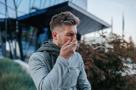 Explore the struggle of a young bearded Hispanic American man battling the flu, manifesting in constant sneezing and coughing on the urban streets.
