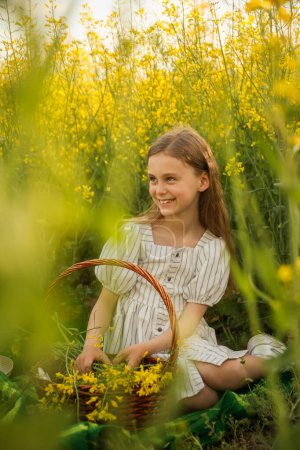 portrait of a attractive charming preteen little girl child in the dress, on a natural yellow background with flowering rapeseed. rustic, spring outside