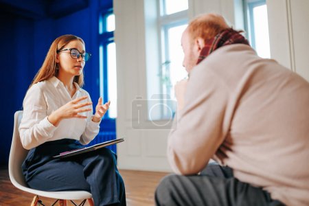 Young specialist psychologist woman gesticulates, explains to the client the essence of the problem. unrecognizable man turned to a psychotherapist for help. Memory impairment, attention impairment.