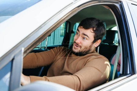 Un buen humor acompaña a un joven en un largo viaje al volante. El conductor está feliz de sentarse al volante de su propio coche y hacer lo que quiere.