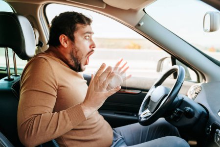 In horror, removing hands from the steering wheel, the young guy screams loudly and bulging his eyes looks ahead. Accidents on the road are always caused by negligence. Sometimes its better to stop.