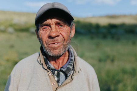 In this natural portrait, the timeless allure of rural life is embodied by a senior shepherd farmer, his weathered features and steadfast gaze a testament to the enduring bond between man and nature.