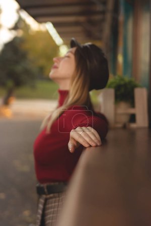 Téléchargez les photos : Belle femme dans le golf rouge posant parmi les magasins avec du café - en image libre de droit