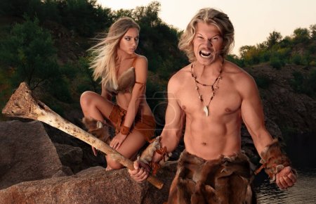 Primitive furious sexy man posing with his beautiful wild woman among rocks and nature