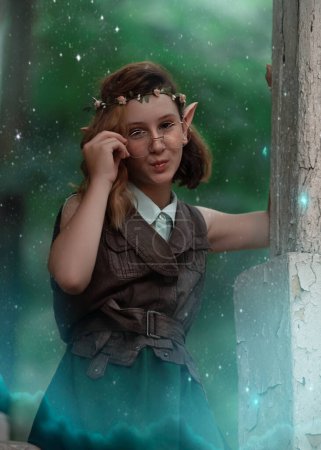 Foto de Chica elfa de fantasía en gafas en el bosque de hadas. Hada pelirroja. Verano naturaleza bosque árbol verde. Pelo rojo, orejas de elfo puntiagudas. - Imagen libre de derechos