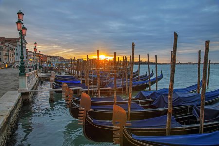 Photo for Venice, Italy - February 27, 2023: Colorful landscape with sunrise sky and gondolas parked near piazza San Marco in Venice. Perspective view - Royalty Free Image