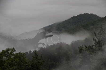 Straszny ogromny tyranozaur we mgle wspina się na zbocze góry pokrytej zielonym lasem