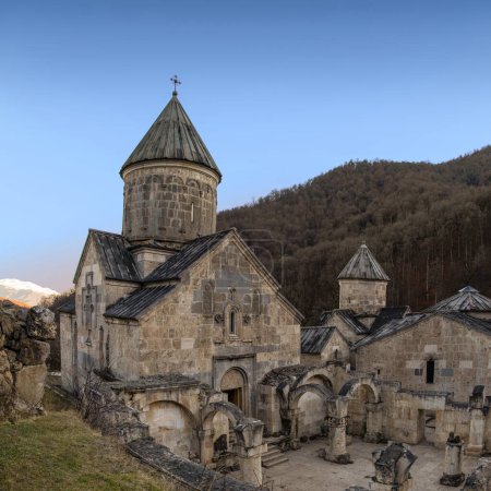 Téléchargez les photos : Le monastère de Haghartsin (XIIIe siècle) au coucher du soleil avec des montagnes en arrière-plan à Dilijan, Arménie - en image libre de droit