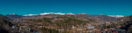 Téléchargez les photos : Dilijan, Arménie - 06 janvier 2024 : Grand panorama de Dilijan par une matinée ensoleillée d'hiver avec ciel bleu, montagnes enneigées et conifères verts - en image libre de droit