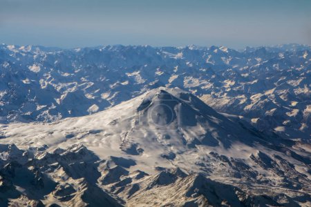 Téléchargez les photos : Vue aérienne sur une montagne depuis l'avion, belle vue fantastique sur la planète. Une énorme montagne au premier plan. Fond parfait pour un texte et un design - en image libre de droit