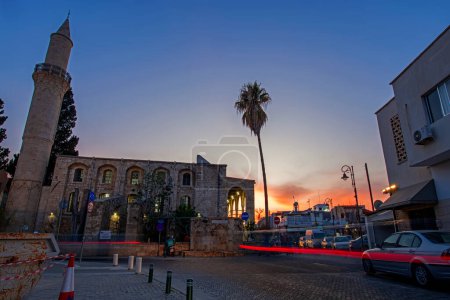 Téléchargez les photos : Larnaca, Chypre - 31 mars 2024 : Scène de perspective nocturne avec la mosquée Djami Kebir et les feux latéraux rouges des voitures brouillées en mouvement. Photographie longue exposition - en image libre de droit