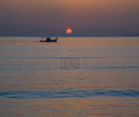 Minimalistisch schöne Szene mit blauem Meer Sonnenaufgang mit Sonne am Horizont mit Silhouette von Fischerboot segeln