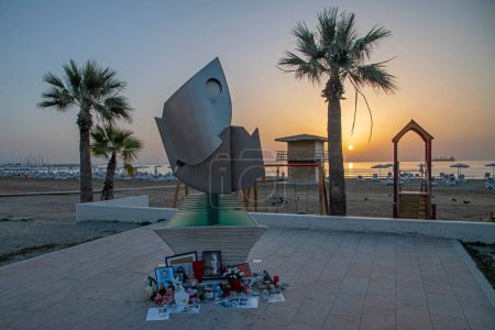 Téléchargez les photos : Larnaca, Chypre - 31 mars 2024 : Mémorial impromptu en mémoire d'Alexei Navalny à la sculpture abstraite "Art à la plage 2" le matin avec lever de soleil sur la mer en arrière-plan - en image libre de droit