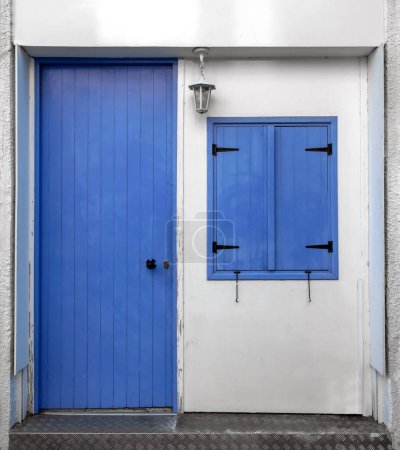 Téléchargez les photos : Vieille porte en bois bleu iconique et fenêtre contre mur blanc. Vue traditionnelle pour les îles méditerranéennes - en image libre de droit