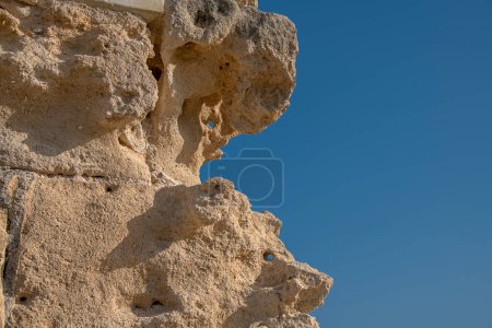 Téléchargez les photos : Gros plan de la pierre altérée de l'ancien aqueduc de Kamares sur fond de ciel bleu. Texture détaillée du grès - en image libre de droit