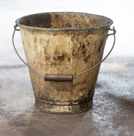 Photo for Very dirty old enamel bucket on industry floor - Royalty Free Image