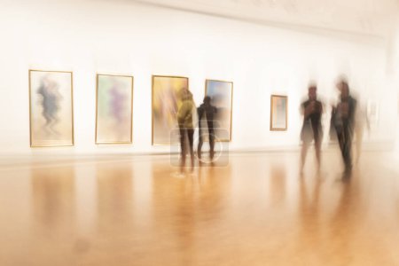 Foto de Exposición de arte o museo con personas en movimiento borroso que recorren las pinturas - Imagen libre de derechos