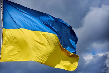 The Ukrainian flag is developing against the cloudy sky.