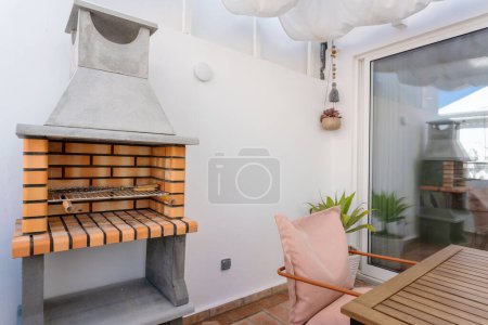Moderner, umweltfreundlicher Grill auf der Terrasse der Wohnung mit Tisch. Hochwertiges Foto